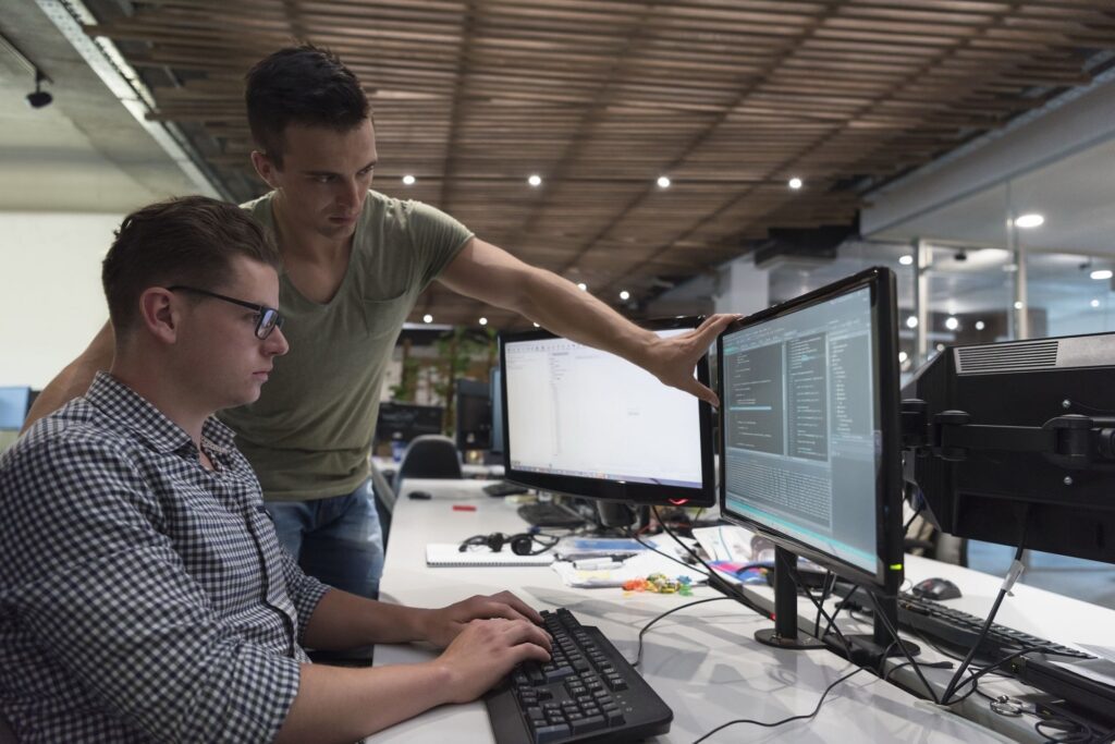 two developers looking at web design on a computer monitor