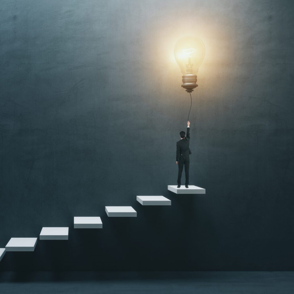 man at top of steps holding cord connected to a light bulb